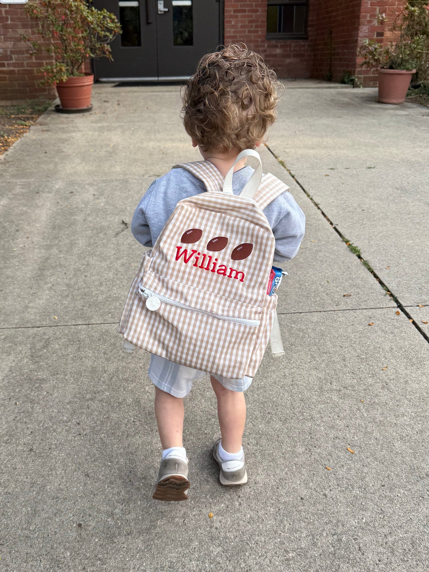 Child wearing a monogrammed TRVL Design Mini Backer backpack